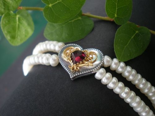 Perlenarmband mit Herzmotiv und goldenene Details in der Mitte geziert von einem Granat