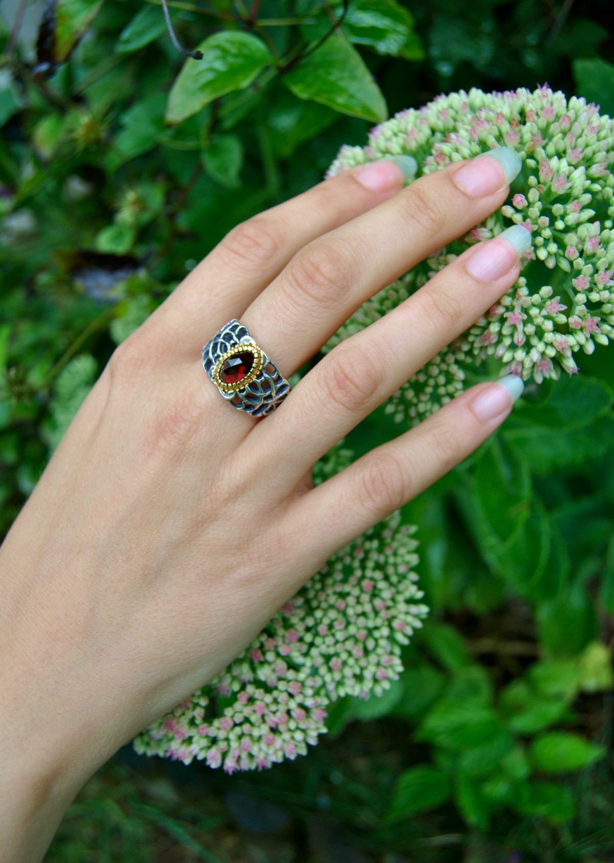 Ring aus Silber mit Gitteroptik und Granat gefasst auf Hand getragen
